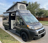 Dark gray pop-top camper van with open side door revealing a compact kitchen. Perfect for RV rental adventures!