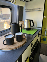 RV rental kitchen: cozy setup with frothy coffee mugs, a kettle, & French press for morning brew.