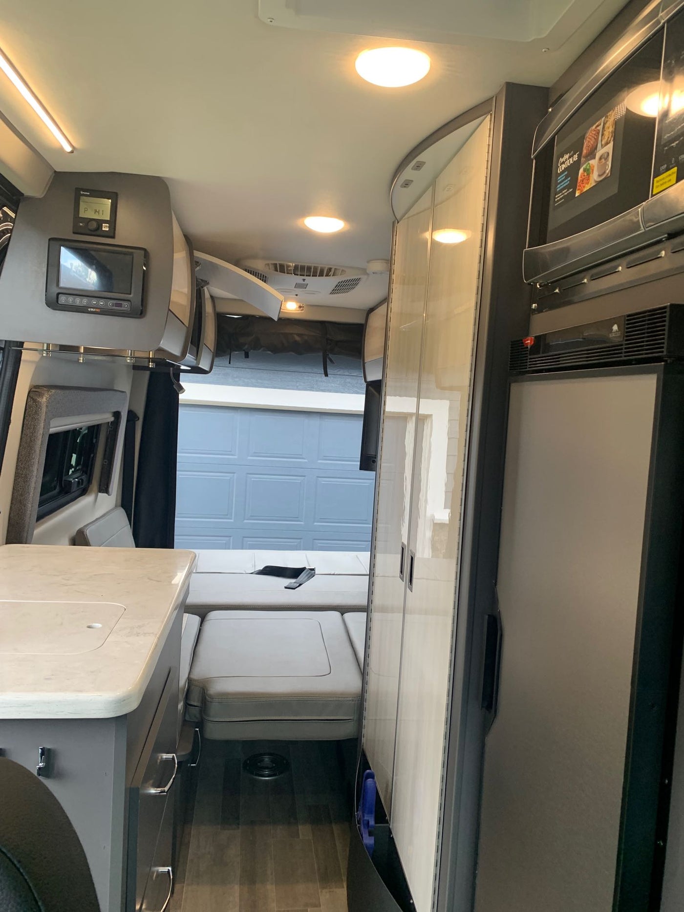  ideal for your next rv rental journey.|Inside a modern **rv rental**: A well-equipped kitchen area with a sink and a cozy rear seating/dining space with seatbelts.|Explore this modern RV rental's spacious interior: a convertible bed — photo 6