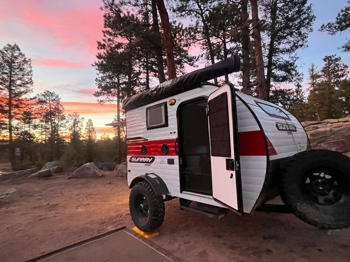 A Sunray Sport teardrop RV rental glows under a stunning pink sunset at a rustic campsite, ready for your outdoor journey. — photo 18