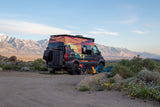 This colorful RV rental is perfectly set up for a desert camping adventure with a fire pit and mountain views.