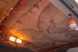 RV rental interior: The ceiling showcases a vintage world map, lit by warm strip and hanging lanterns, perfect for travel.