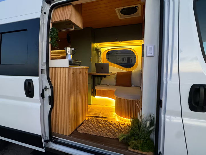 Step inside a cozy RV rental camper van, featuring a modern wood and green interior with kitchen and illuminated living area.