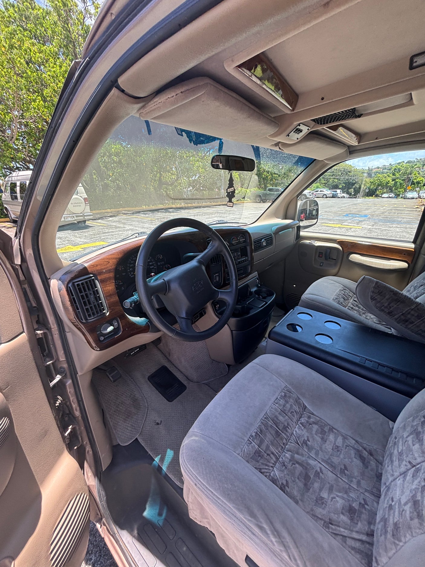 Inside a spacious RV rental van, featuring its dashboard with wood trim, steering wheel, and front seats with a large console.