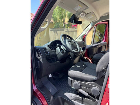 Inside a red RV rental van: driver's seat, steering wheel, and dashboard. Ready for your next journey!