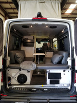 Interior of a custom rv rental camper van, showing pop-top, lounge seating, table, and entertainment.