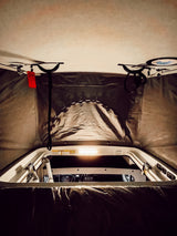 Cozy RV rental interior view: looking from the bed area towards the lit front cabin and pop-top ceiling.