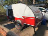 This compact teardrop RV rental is parked at a serene campsite, ready for your outdoor adventure.