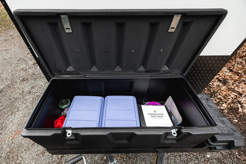 Opened front storage box on an RV rental travel trailer, neatly organized with blue containers, a red bag, and manual. — photo 6