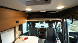Step inside this cozy RV rental camper van, featuring a driving cabin, dining area with fresh fruit, and ample overhead storage.