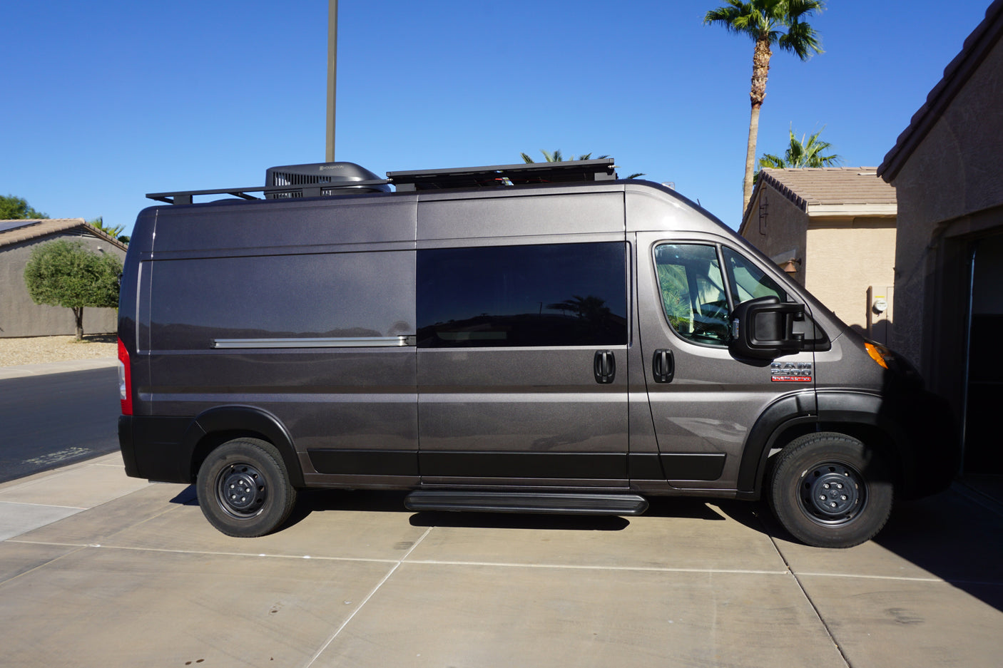 Sleek gray custom camper van, a perfect RV rental for road trips. Features rooftop AC, solar, and a roof rack.