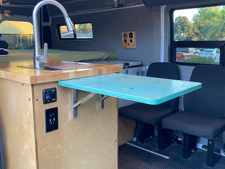 RV rental interior featuring a kitchenette with sink, pull-out dining table, and seating.