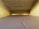 Inside an RV rental pop-top, showing the cozy upper sleeping area with light filtering through the fabric walls and ceiling.