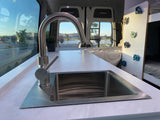 Inside a stylish RV rental camper van: Kitchen sink, bright windows with a view, & fun climbing wall.