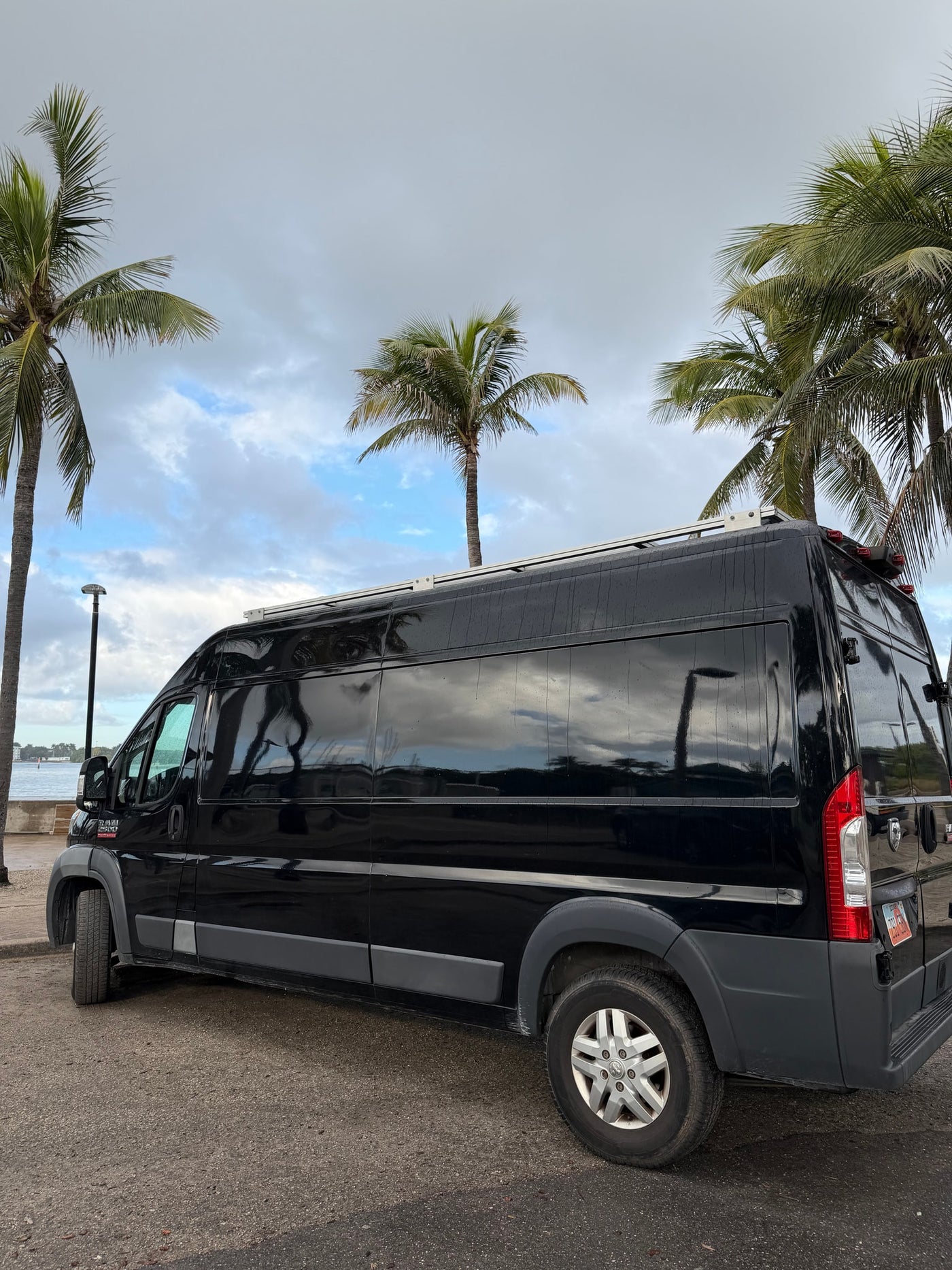  and palm trees through the wet windshield.|Dashboard and rain-splashed windshield of an RV rental. A digital rearview mirror shows a wide — photo 20