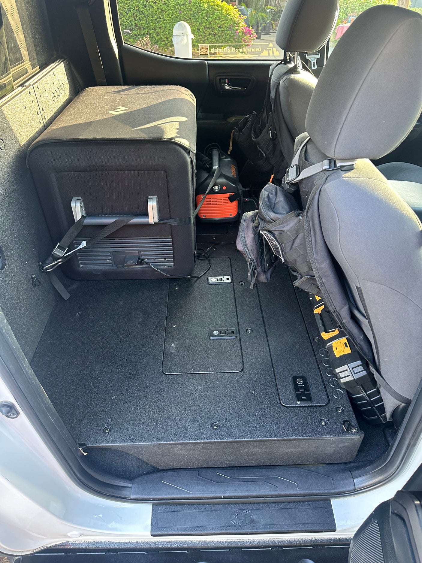 Rear interior of an RV rental truck: a flat cargo platform with secured portable fridge, power station, and adventure gear for trips.