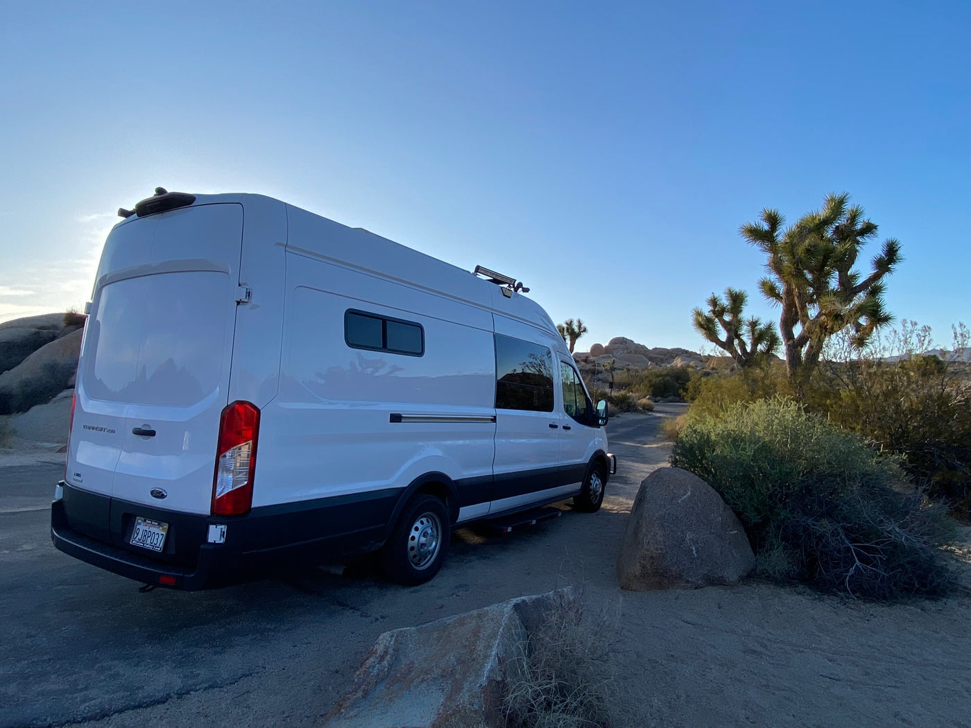  with modern buildings behind it.|Experience comfort in our RV rental! This full-size bed with mesh cover — photo 6