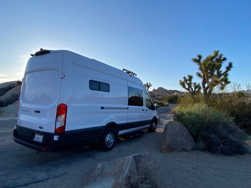 with modern buildings behind it.|Experience comfort in our RV rental! This full-size bed with mesh cover — photo 6