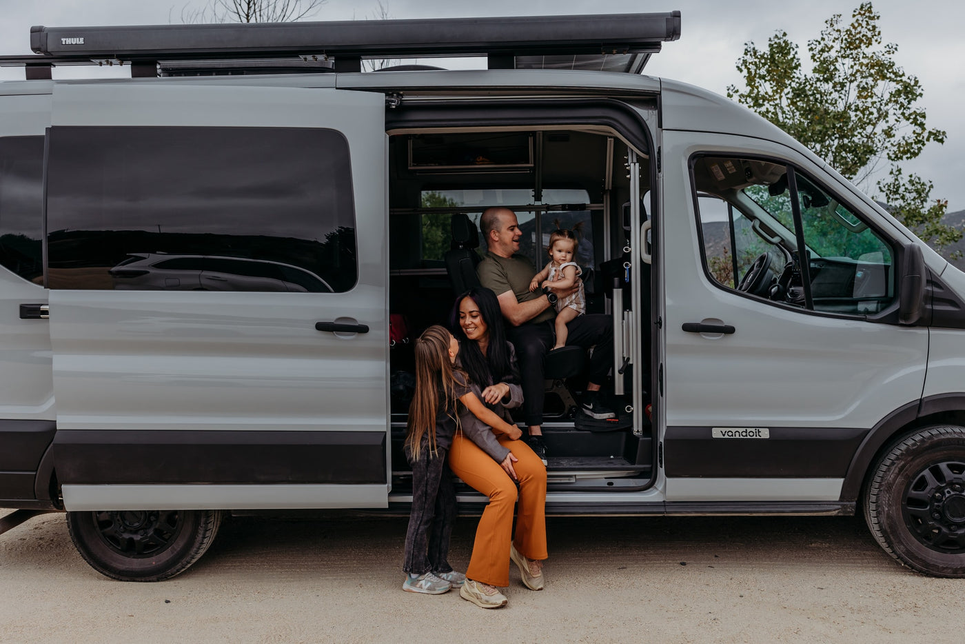 Family moments in a spacious RV rental camper van. Dad holds baby, while mom and daughter relax by the open door. — photo 19