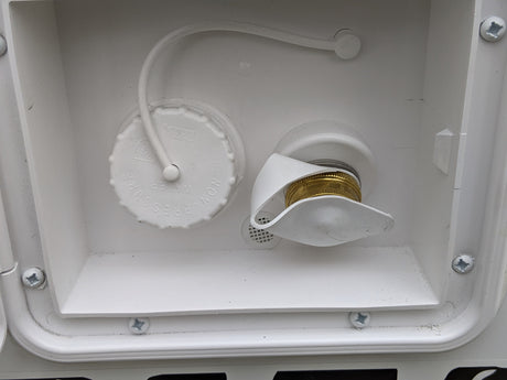 RV rental water fill and city water hookup. White compartment showing non-pressure water cap and brass hose inlet for an RV.