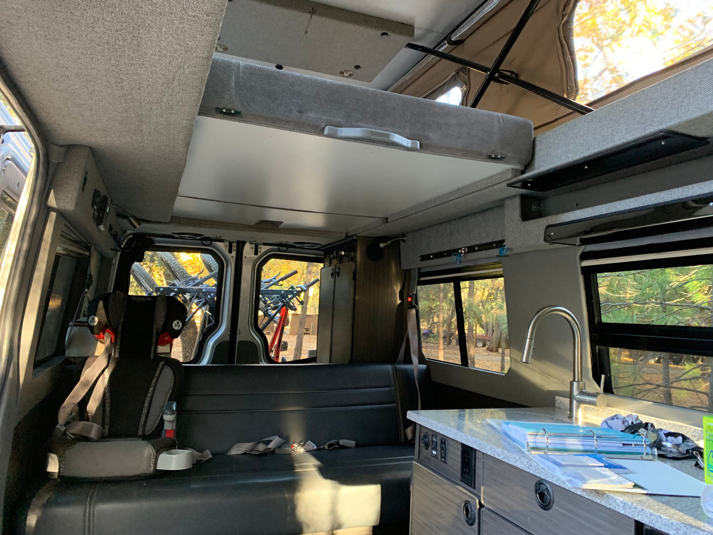Spacious RV rental interior featuring a fold-down bunk bed, kitchen, seating, and bike storage inside.