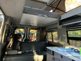 Spacious RV rental interior featuring a fold-down bunk bed, kitchen, seating, and bike storage inside.