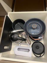 Organized rv rental kitchen drawer: pans, kettle, induction cooktop, cutting board, & slicer for compact living.