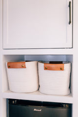 RV rental interior featuring neat storage: two white rope baskets on a shelf above a black Smod mini-fridge.
