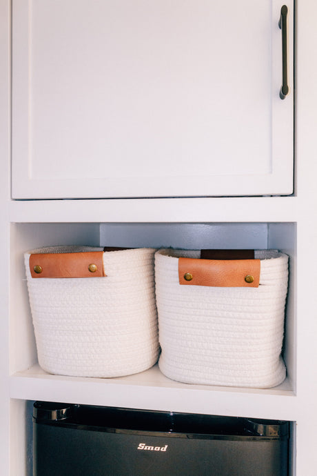 RV rental interior featuring neat storage: two white rope baskets on a shelf above a black Smod mini-fridge.