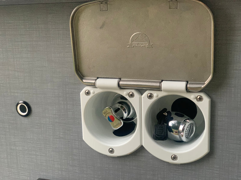 RV rental outdoor shower with lid open, revealing a chrome mixer tap (hot/cold) and a small shower head. — photo 17