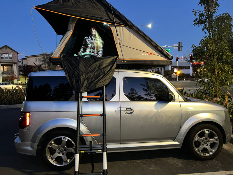  perfect for RV rental trips.|A woman inside a car-top tent on a silver Honda Element — photo 5