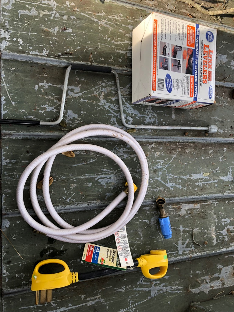 Essential RV rental gear: Levelers, power adapters, water hose, and pressure regulator for easy setup.
