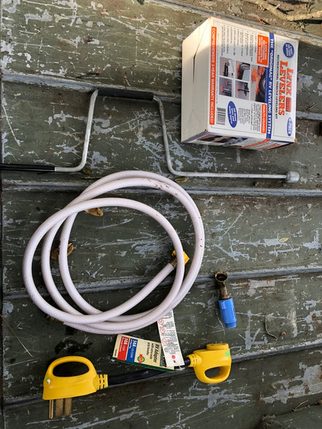 Essential RV rental gear: Levelers, power adapters, water hose, and pressure regulator for easy setup.