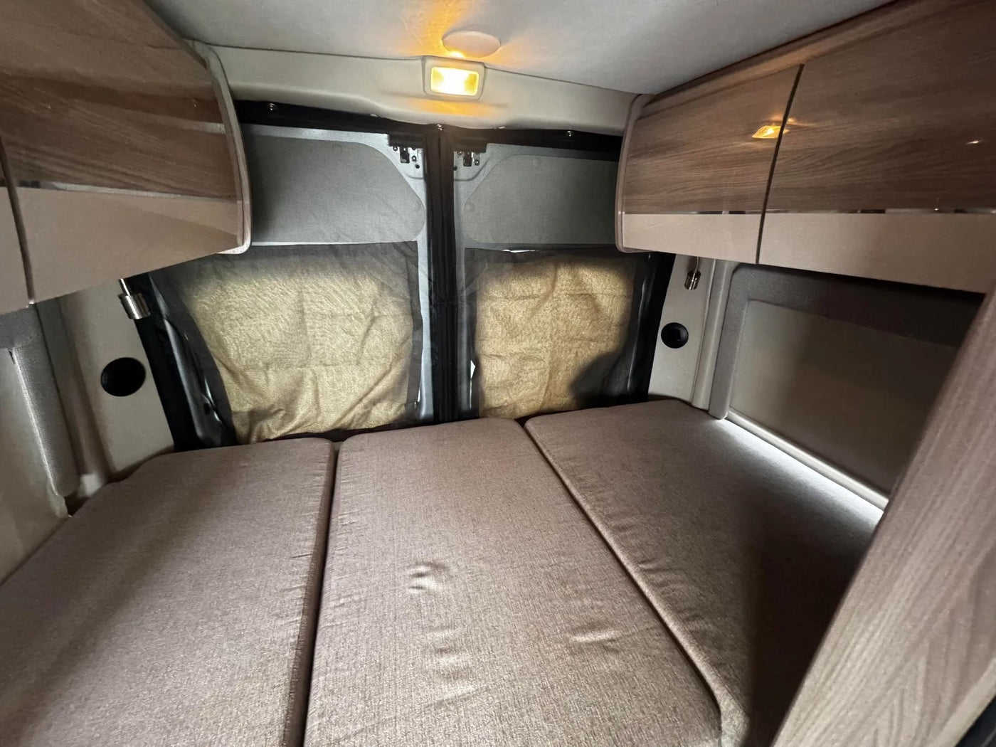Experience comfort in this **rv rental** interior: a fold-out bed, overhead storage, and screened rear windows for privacy. — photo 10