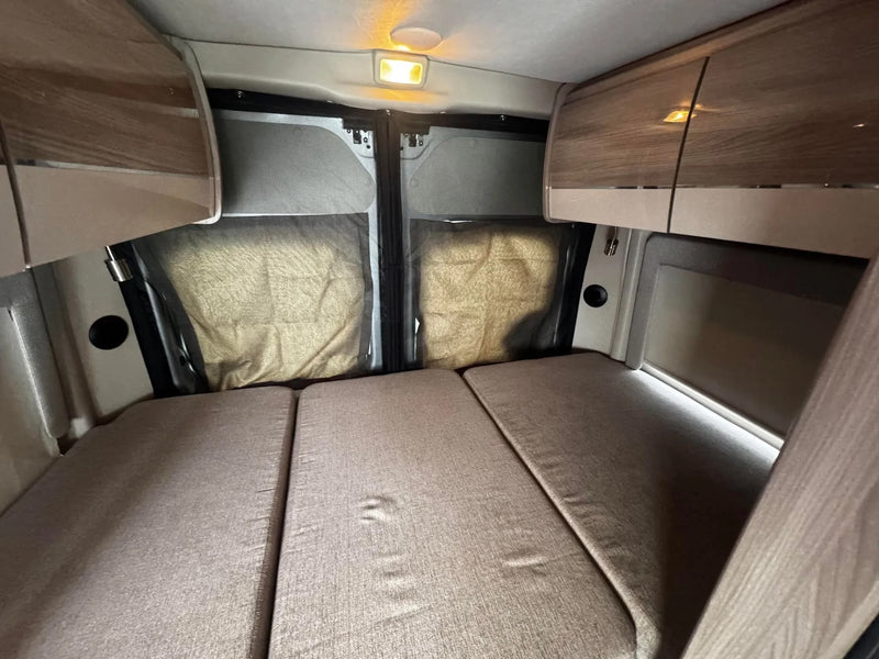 Experience comfort in this **rv rental** interior: a fold-out bed, overhead storage, and screened rear windows for privacy. — photo 10