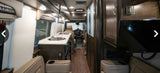 Detailed rv rental interior: kitchen with sink, cozy seating, overhead cabinets, & driver's cockpit view.