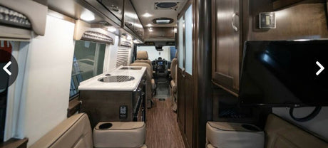 Detailed rv rental interior: kitchen with sink, cozy seating, overhead cabinets, & driver's cockpit view.