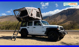 A white Jeep Wrangler with a deployed rooftop tent, parked on sand near mountains. Your next adventure RV rental for camping is ready!