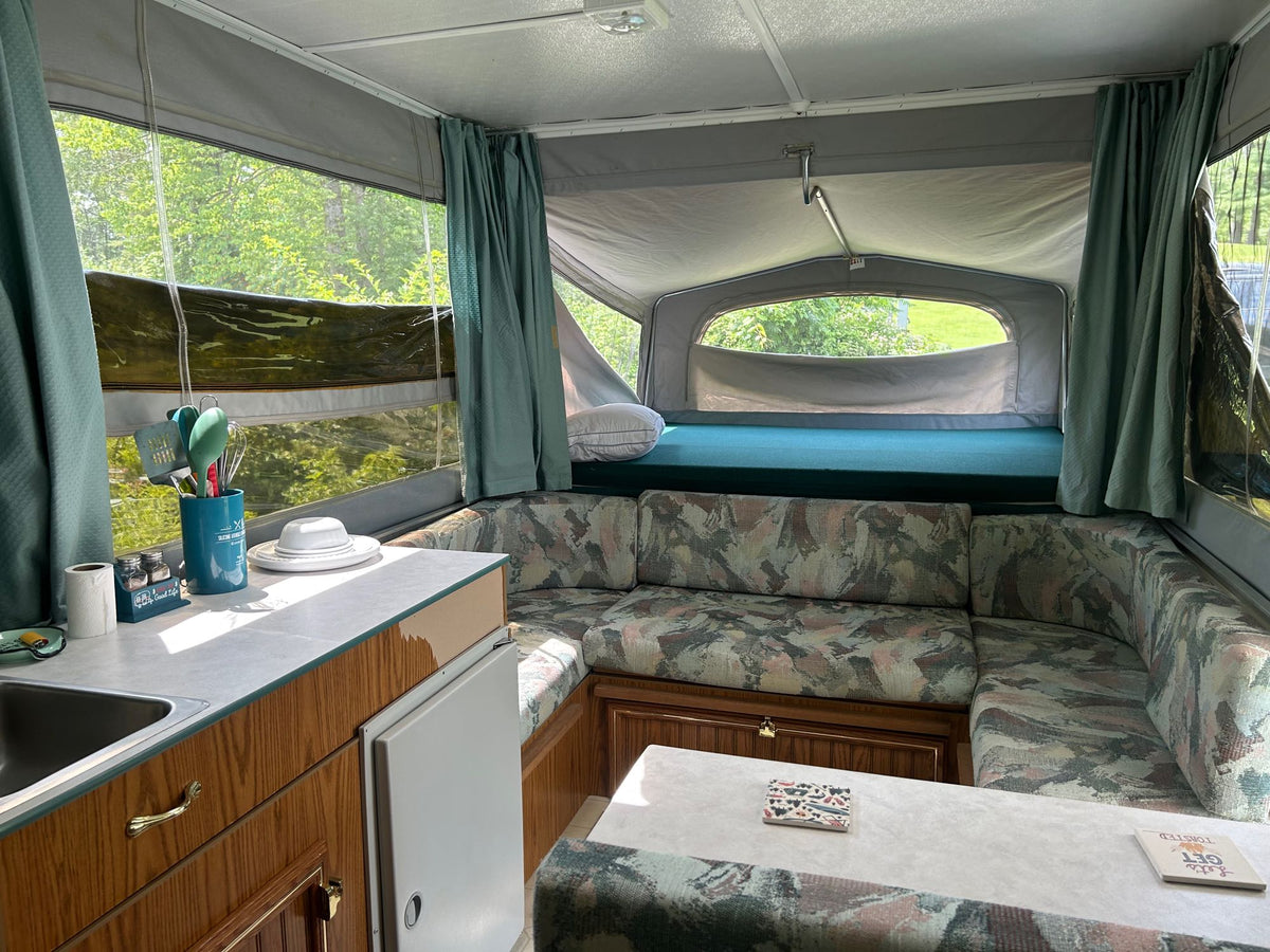 Step into this inviting RV rental: a pop-up camper with kitchen, L-shaped dinette, and comfortable rear bed. — photo 6