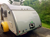 Rear view of a light grey nuCamp teardrop travel trailer, an ideal RV rental, showing yellow fenders.