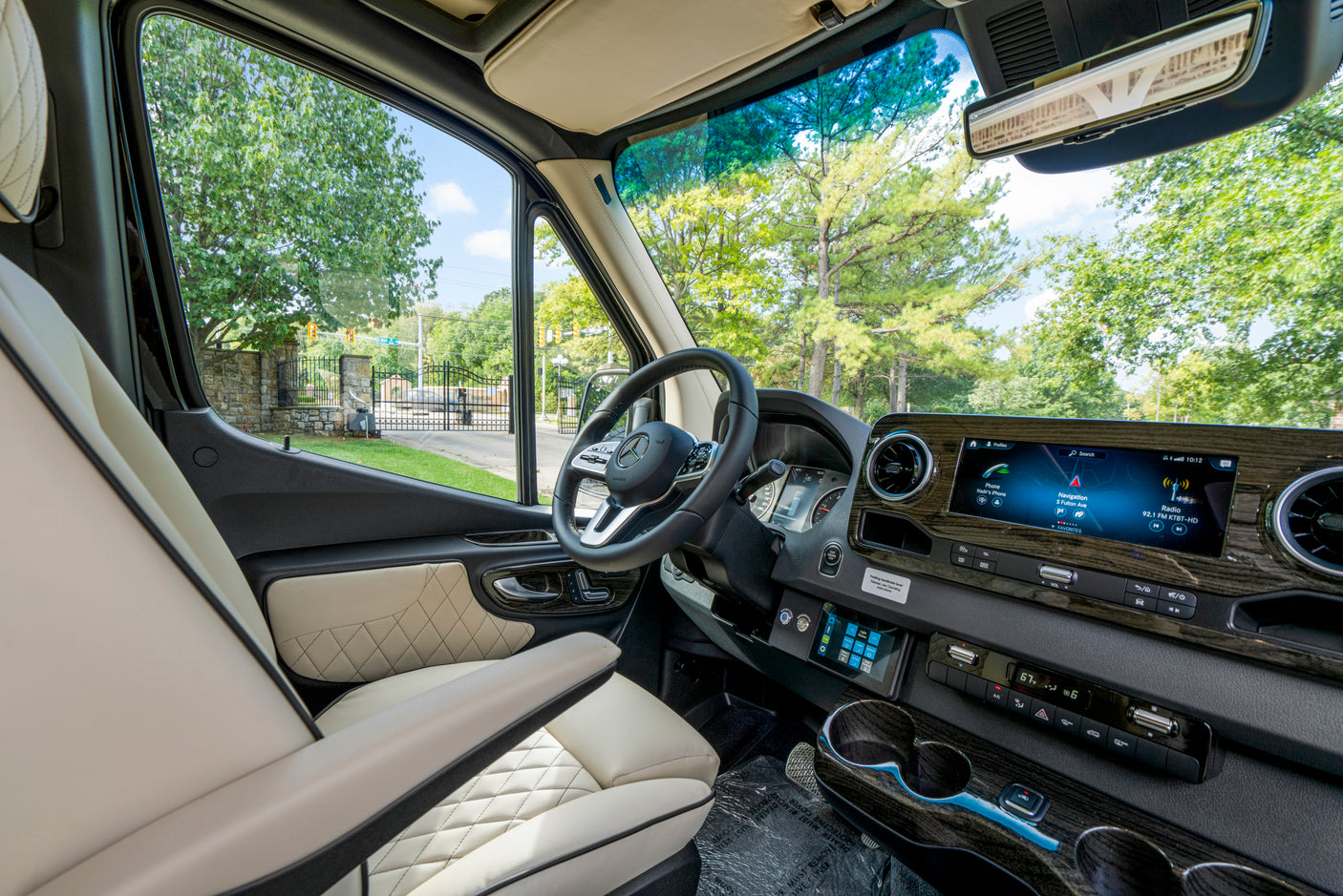 Explore this modern rv rental's cockpit: plush seats, wood-grain dashboard, and advanced infotainment with navigation.