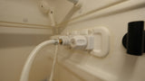 Close-up of an RV rental shower: The beige interior features water controls, a flexible hose, and a wall-mounted showerhead.