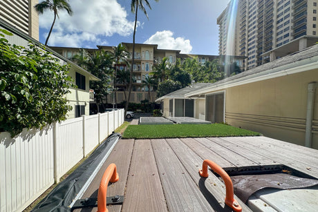 From an RV rental's deck: A sunny view of tropical homes, tall buildings, and lush foliage in an urban setting.