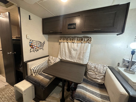 Cozy RV rental interior showcasing a dinette, overhead cabinets, and a bunk bed area for comfortable travel.