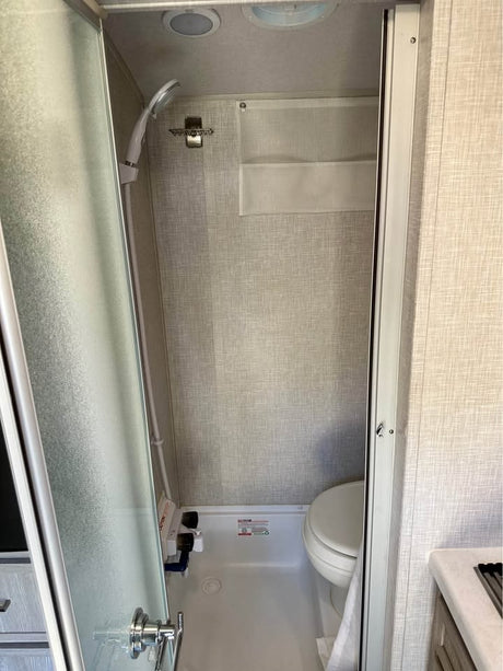 Explore this RV rental's efficient wet bath, featuring a shower, toilet, and handy wall storage.
