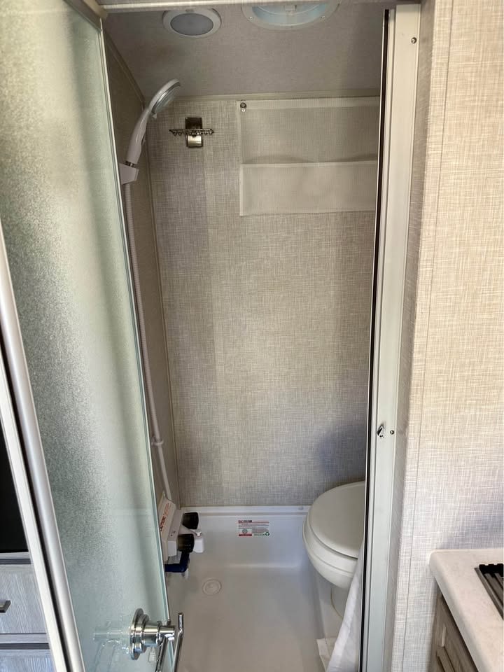 Explore this RV rental's efficient wet bath, featuring a shower, toilet, and handy wall storage. — photo 7