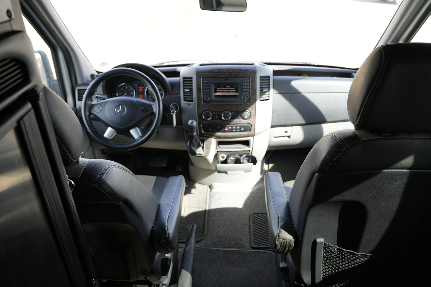 RV rental interior: driver's cockpit with Mercedes-Benz steering wheel, dashboard controls, and front seating visible.