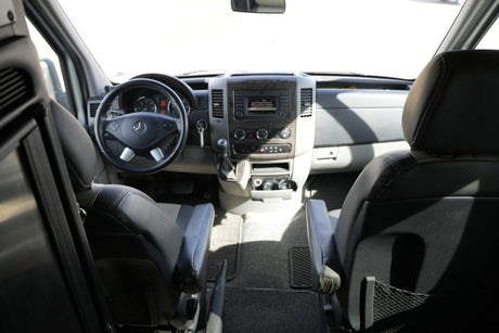 RV rental interior: driver's cockpit with Mercedes-Benz steering wheel, dashboard controls, and front seating visible.
