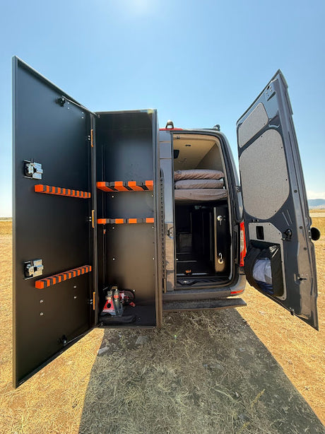 Inside this RV rental van: custom storage unit with orange racks, a comfy bed, perfect for gear & rest on the go.