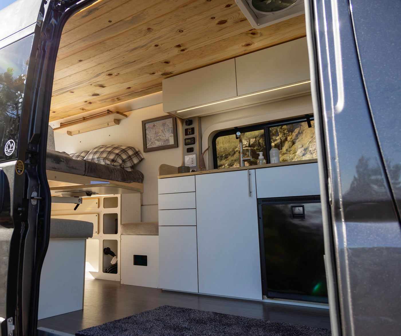 Bright RV rental camper van interior: wood ceiling, bed, functional kitchen, and ample storage for mobile living. — photo 12